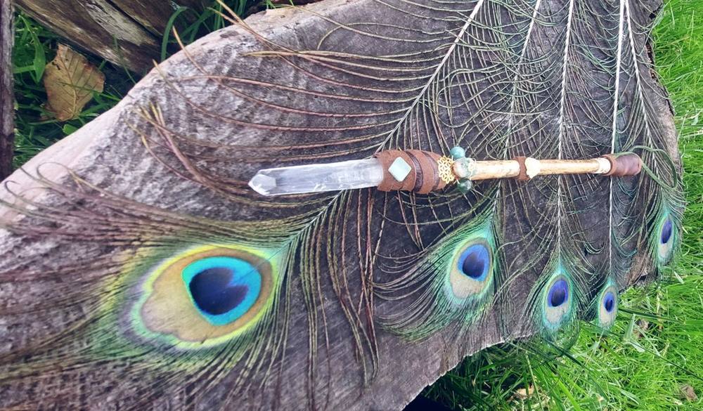Clear quartz wand on peacock feathers